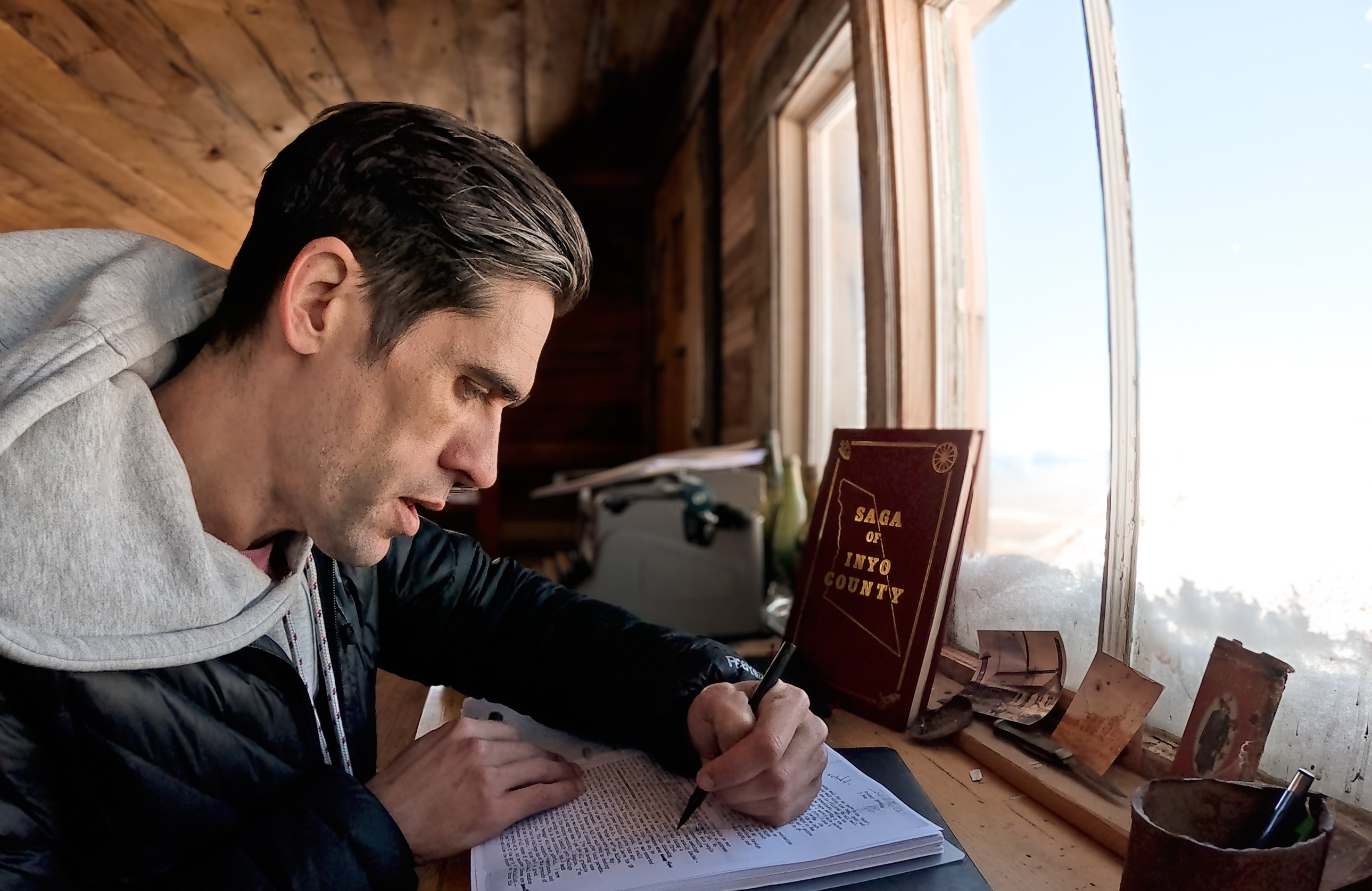 Ryan Holiday writing at his desk overlooking a wintry landscape